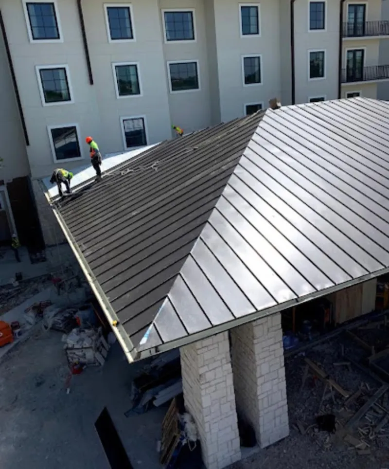 Crew installing standing seam metal roof panels on a commercial project in West Rockhill